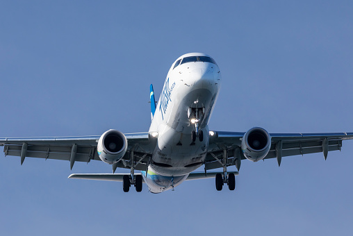 Portland, Oregon USA - February 25, 2023: An Embraer E175 comes in for landing on a crisp winter day at Portland International Airport.