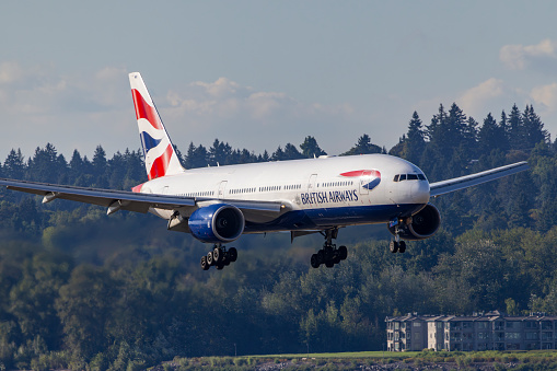 London, England - March 2019: Boeing 777 long haul airliner operated by British Airways taxiing for take off past tail fins of the company's other aircraft.