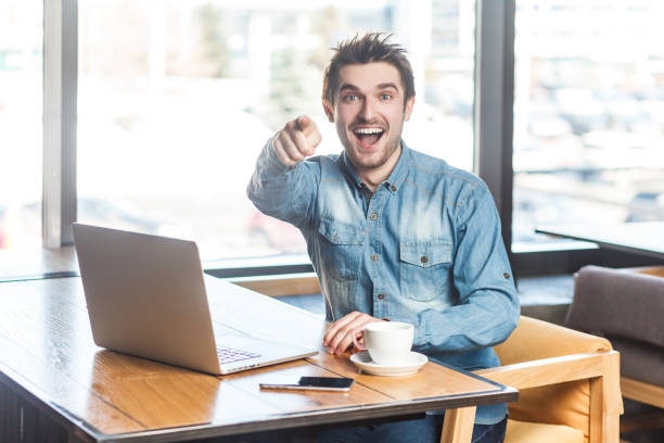 istock Overjoyed smiling young man working on laptop, looking at pointing to camera, choosing you. 1935889732