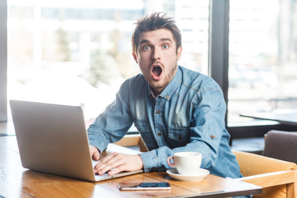 istock Amazed astonished surprised man working on laptop, looking at camera with big eyes and open mouth. 1935889736