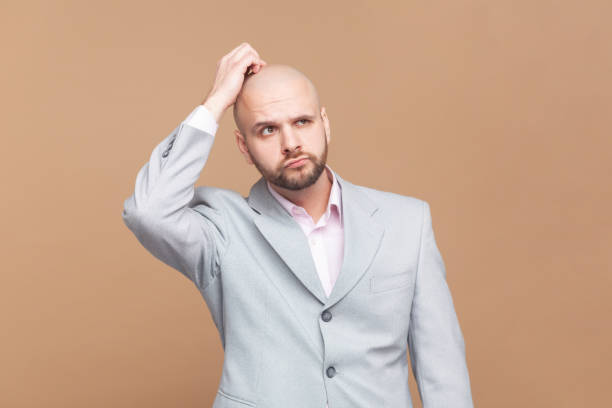 istock Man rubbs head, tries to remember necessary information, looks in displeasure. 1935899719