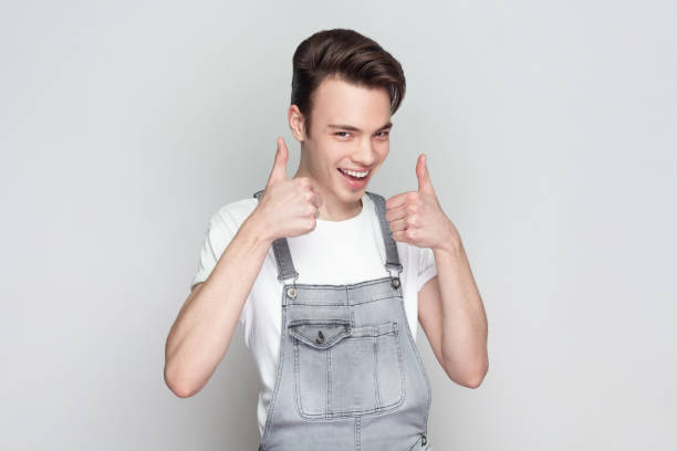 istock Young brunette man standing keeps thumb raised, being in good mood, shows his agreement. 1935907582