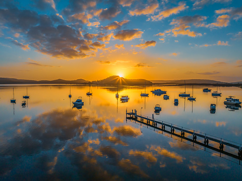 Aerial sunrise waterscape with boats, reflections and low cloud