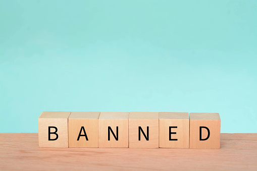 Wooden block with text BANNED. A ban refers to a formal or official prohibition or restriction on a particular activity, action, item, or person. It is an authoritative decision made by a government