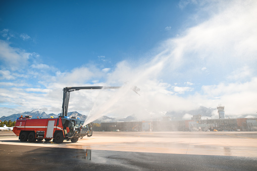Firetruck spraying water at the airport runway.