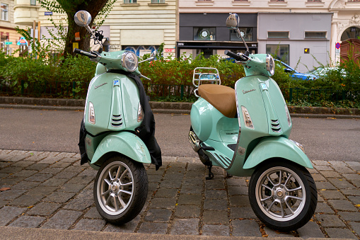 Two Vespas parked on a downtown street in a European city. Vienna, Austria. September 24, 2023.
