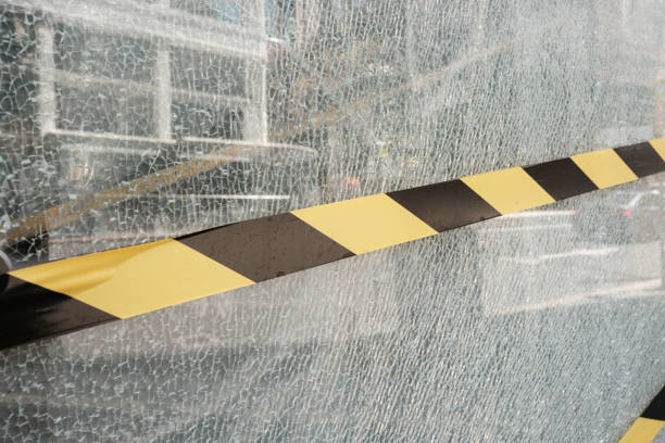 Close-up on a section of broken glass with black and yellow tape across it.