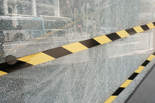 Close-up on a section of broken glass with black and yellow tape across it.