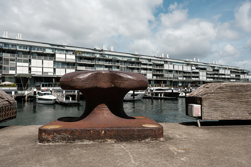 Sydney, Australia -January 07,  2024: close-up on an old mooring bollard at Walsh Bay, Sydney, with boats and apartments in the background.