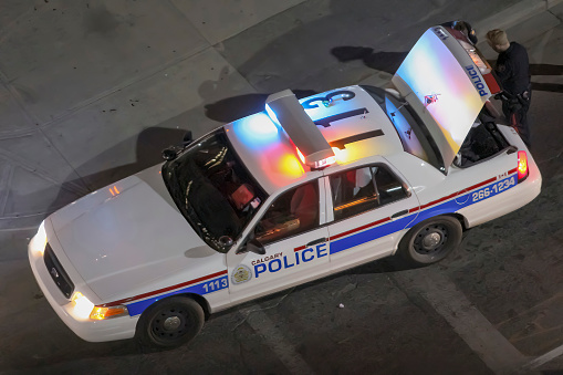 Calgary, Alberta, Canada. Jun 05, 2011. Looking down from above, a Calgary police vehicle with its back door open, as an officer responds to an emergency call in downtown Calgary at night.