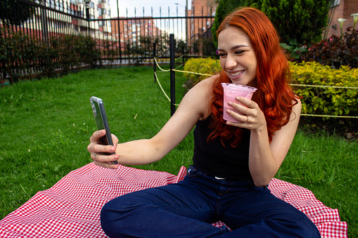 beautiful young woman outdoor drinking yogurt and taking pictures