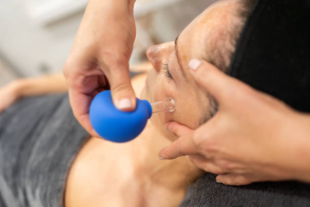 Client receiving facial cupping in beauty parlor From above of hand applying cupping therapy with blue facial cup to woman with dark hair during skin treatment in beauty spa cupping therapy stock pictures, royalty-free photos & images