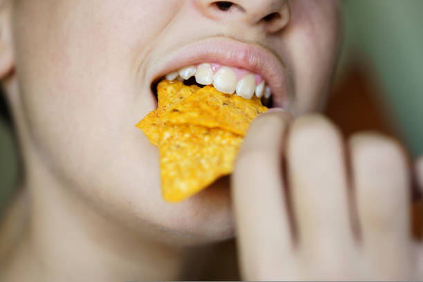 istock Crop anonymous girl biting yummy crunchy Mexican tortilla chips 1936129744