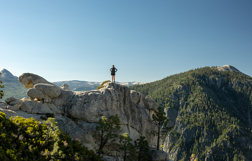Woman Stands on Rocks at Yosemite Point on clear summer day
