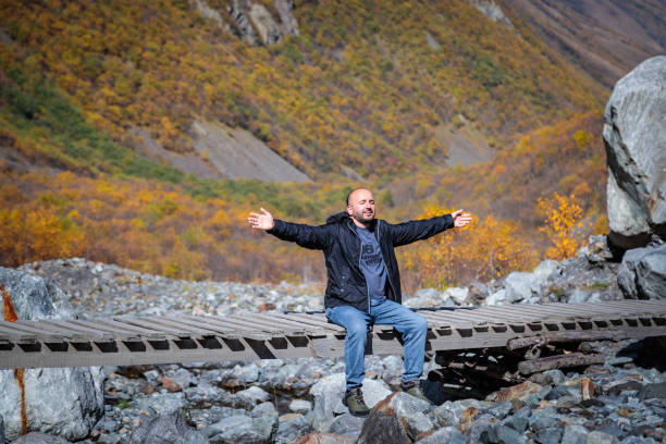 Man enjoying nature while sitting on bridge in mountains