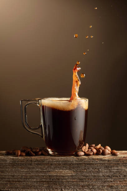 Espresso coffee glass cup with splashes on a brown background. stock photo