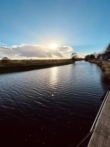 Sun setting in the distance behind a wide cloud over a canal in southern Netherlands.