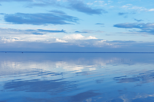 Nature picturesque landscape, clouds reflected on water surface, windless summer weather, tranquil blue trend sky background, mirroring sky on water, white blue nature gradient, aesthetic skyline