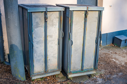 Two light gray transformer boxes on the side of pavement in a sunny day. High quality photo