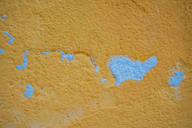 The yellow wall surface has peeling paint due to it being worn out.Texture on peeled yellow antique wallsm texture background. Textured Background. High quality photo