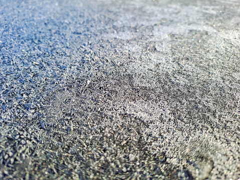 The surface of the cobblestones is covered with ice, icy conditions, black ice. Paving slabs in the snow in winter. Background. Rainy days cause water waves on the concrete road surface. close-up