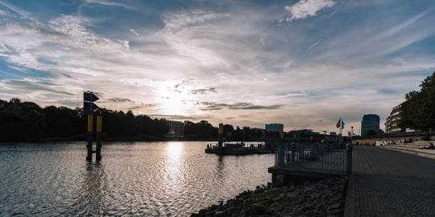 Bremen, Germany, Europe - September 20, 2023: photo of the german street. River Weser, boat and pier. City park and beach, blue sky with clouds.