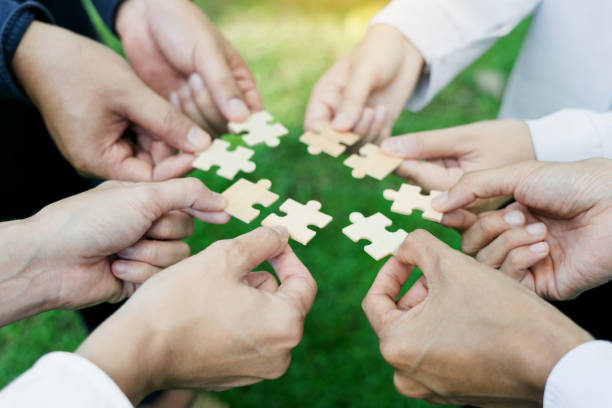 istock group of business people assembling jigsaw puzzle. The concept of cooperation, teamwork, help and support in business. 1936242636
