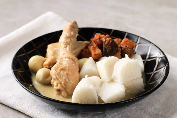 Photo of Lontong Opor, Indonesian White Curry with Chicken Drumstick and Quail Eggs, Chicken and Boiled Egg Cooked in Coconut Milk from Indonesia, Served with Lontong or Ketupat and Sambal. Popular Dish for Lebaran or Eid al-Fitr