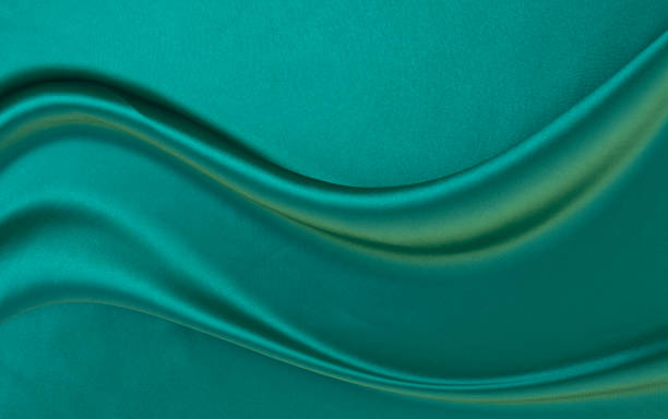 istock Black green satin dark fabric texture luxurious shiny that is abstract silk cloth background with patterns soft waves blur beautiful. 1936275914