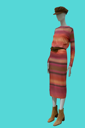 Full length image of a female display mannequin wearing long-sleeved colored dress over green background