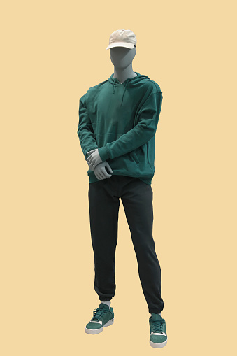 Full length image of a male display mannequin wearing green hoodie with kanga pocket isolated on yellow background