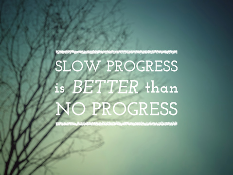 Inspirational motivational quote concept - Slow progress is better than no progress text with blurry nature background. Stock photo.