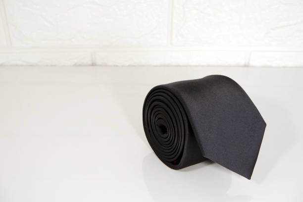 istock Single plain black color necktie rolled on gift box with white background close up view 1936348449
