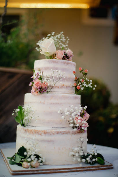 istock White three tiered naked wedding cake with tiny pink, orange roses decoration 1936390777