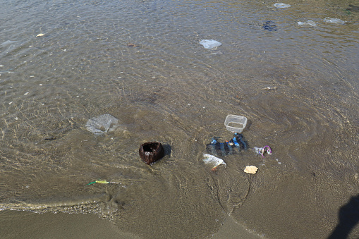 Plastic waste and bottles are strewn on the beach