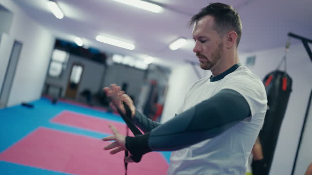 Confident Male Fighter in Sportswear Wrapping Boxing Wraps Before Training in Sports Club