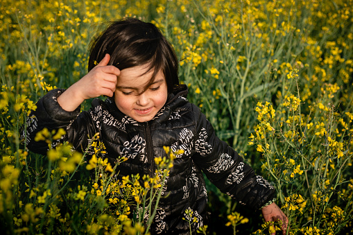 upper view on walking in a blooming field smiling child with dark hair on a sunny day