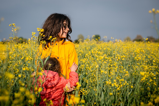 two children hugging each other standing in a yellow blooming field