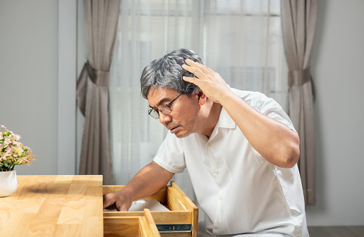 Asian older man finding something that he forgot it in drawers.