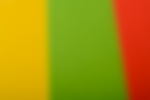Blurred background of colored paper combining three colors: green, red, and yellow.
