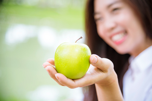 young asian woman eating Apple Healthy. Girl workout holding organic apple fruit healthy lifestyle. Wellness Asian women eat red apple smile face look at camera. Beauty health care lifestyle concept