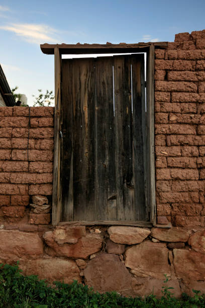 An abandoned house in the town of Cerocahui is falling into pieces. An old wooden door with its frame still stands. It is built with adobe blocks.