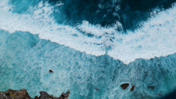 Turquoise ocean sea water white wave pattern splashing deep blue sea. Seascape dark ocean background wave splash on rock. Tropical sea beach in summer seaside outdoor. Water Surface blue wave pattern