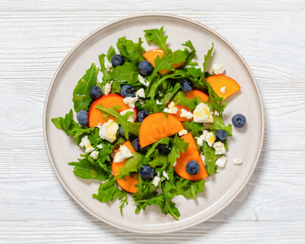 istock arugula persimmon cheese berries salad, top view 1936723126