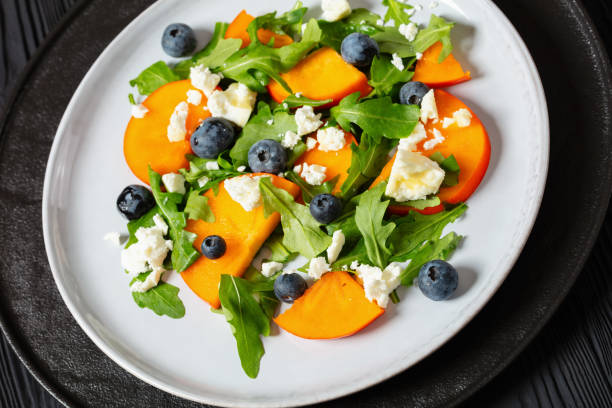 istock arugula persimmon cheese berries salad, top view 1936723639