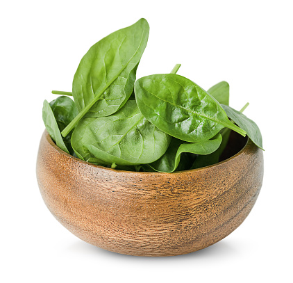 wooden plate with fresh spinach leaves on a white isolated background