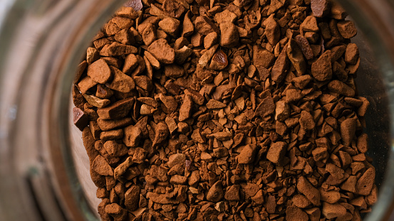 Macro shot background of ground coffee in jar from top angle.