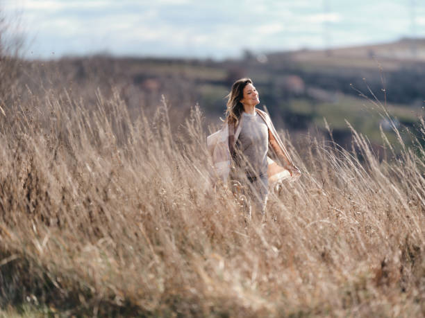 istock Young happy woman walking through tall grass on a hill. 1936748263