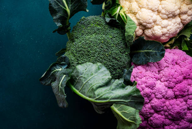 Purple and white cauliflower, broccoli cabbage from farm market on old rustic green table, top view