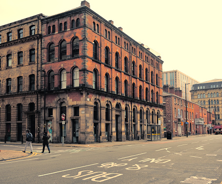 Manchester, United Kingdom - 12 29 2023 : Large, squared red-brick building. In the foreground is a bus lane.
